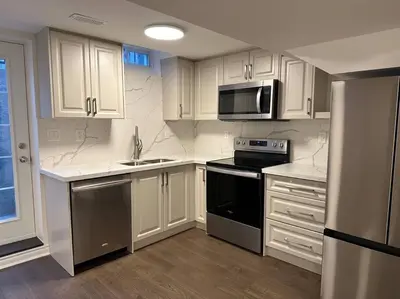 a kitchen with white cabinets and a black stove top oven at Cozy Home away in Ajax 2 BR 1 bath 4 guests in Ajax