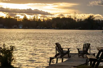 a group of chairs sitting on a dock near the water at Luxury Lakefront with Sauna & EV in Washago