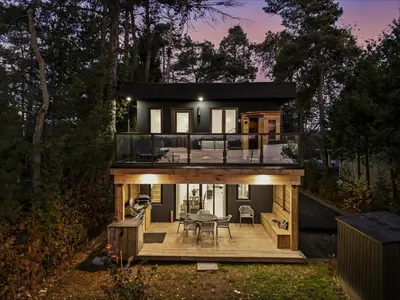 a house in the woods with a deck at Luxury Lakefront with Sauna & EV in Washago