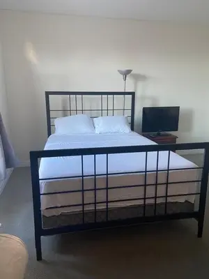 a bed with a black frame and a desk with a computer at Divinity Hut in Brampton