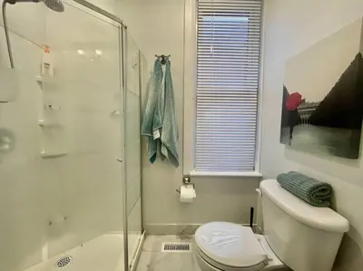 a bathroom with a toilet and a glass shower at Stylish 3-bdrm suite w free Parking in Kitchener