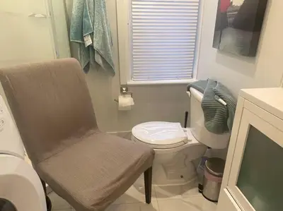 a small bathroom with a toilet and a chair at Stylish 3-bdrm suite w free Parking in Kitchener