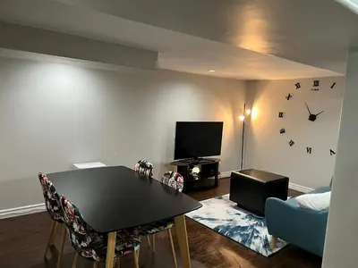 a living room with a table and a clock on the wall at Home by Dolly in Toronto