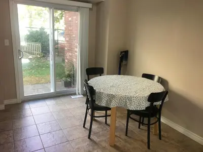 a dining room with a table and chairs and a window at Room in neat comfy house in Kitchener