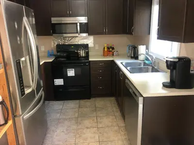 a kitchen with a stainless steel refrigerator and a sink at Room in neat comfy house in Kitchener