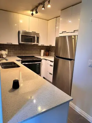 a kitchen with a stainless steel refrigerator and white cabinets at Quiet Room In A Guest House in Mississauga
