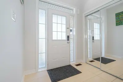 a hallway with a white door and a mirror at Meadowcrest Semi in Mississauga