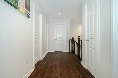 a hallway with white walls and a hard wood floor at Meadowcrest Semi in Mississauga