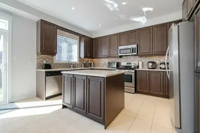 a kitchen with wooden cabinets and a stainless steel refrigerator at Meadowcrest Semi in Mississauga