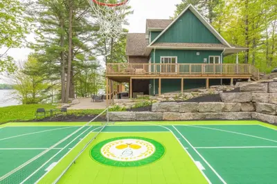 a house with a tennis court in front of it at LUX Lakefront Sleeps18 Pickleball HotTub Sauna Gym Arcade Basketball Volleyball in Buckhorn