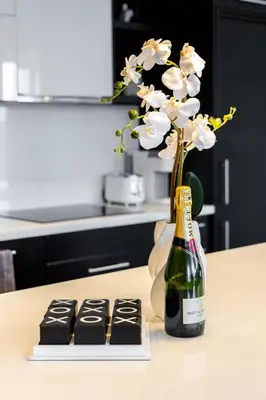 a bottle of champagne next to a vase with flowers at PARC LOFT Penthouse with 4bd-WFH-PS5-CN Tower Views in Toronto
