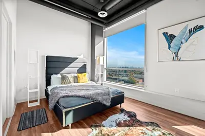a bedroom with a bed and a large window at Finch West Residence Suites - Hotel DUKE in Toronto