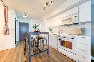 a kitchen with white cabinets and a counter with stools at The Hideaway Hub in Toronto