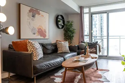 a living room with a black leather couch and a table at The Hideaway Hub in Toronto