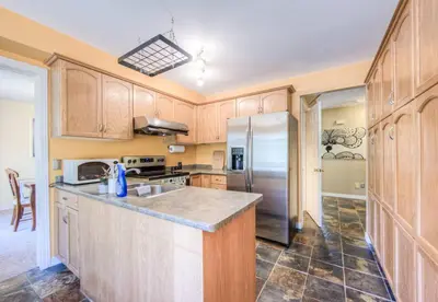 a kitchen with wooden cabinets and a stainless steel refrigerator at 45 per Off Monthly Stay - 7 Beds - BBQ in Kitchener