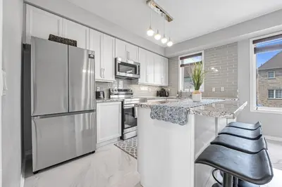 a kitchen with white cabinets and a stainless steel refrigerator at Elegant 3Bedroom with Smart TV and Backyard in Mississauga