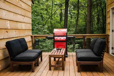 a patio with two chairs and a grill and a table at The Green Acres Cabin in Hamilton
