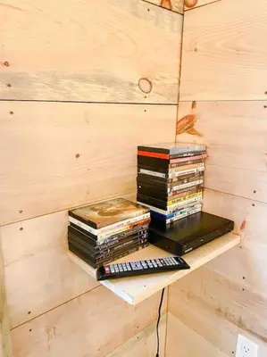 a stack of books sitting on a shelf in a room at The Green Acres Cabin in Hamilton