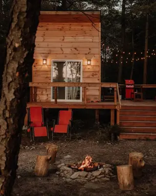 a cabin with chairs and a fire in front of it at The Green Acres Cabin in Hamilton