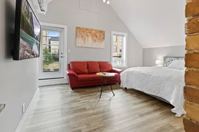 a bedroom with a bed and a red couch at ENTIRE BACHELOR UNIT EN-SUITE ACROSS FROM GOOGLE - br4 in Kitchener