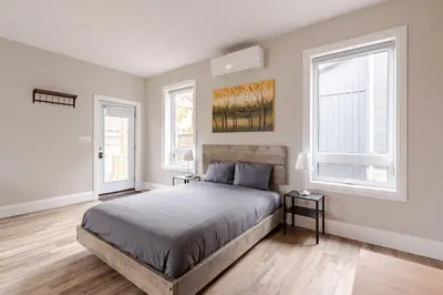 a bedroom with a bed and two windows at ENTIRE BACHELOR UNIT EN-SUITE ACROSS FROM GOOGLE - br3 in Kitchener