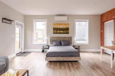 a bedroom with a bed and two windows at ENTIRE BACHELOR UNIT EN-SUITE ACROSS FROM GOOGLE - br3 in Kitchener