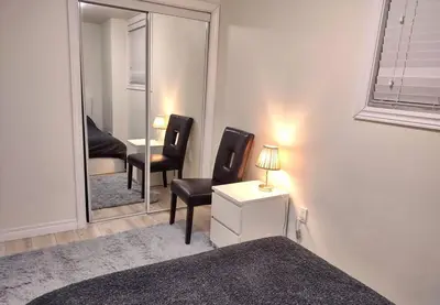 a bedroom with a mirror and two chairs and a table at Basement Waterloo Near 24-7 Restraints in Waterloo