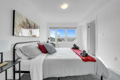 a white bedroom with a large bed and a window at Posh 4 Bed Home with Backyard in Great Location in Burlington