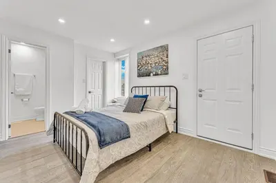 a white bedroom with a bed and a door at Luxury Comfort 3 BR Near Hospitals Tims Field GO in Hamilton