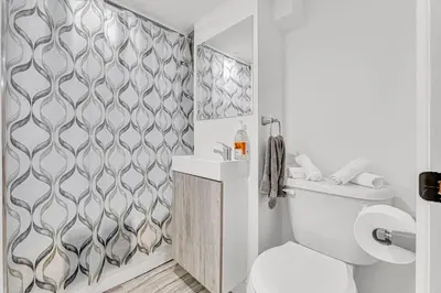 a white bathroom with a toilet and a wall at Luxury Comfort 3 BR Near Hospitals Tims Field GO in Hamilton