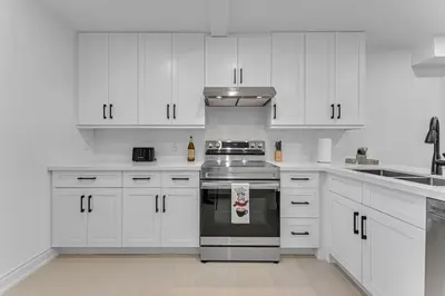 a white kitchen with a stove and white cabinets at Luxury Comfort 3 BR Near Hospitals Tims Field GO in Hamilton