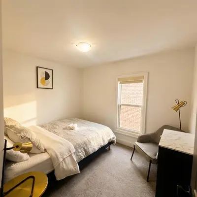 a bedroom with a bed and a chair and a window at Beautiful modern 2Bdr sunny home with French decor in Hamilton