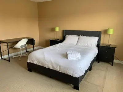 a bedroom with a large bed with white sheets and a chair at Huge Family home sleeps 10 with 3 parking spots in Kitchener