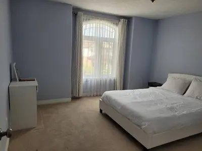 a bedroom with a white bed and a window at Huge Family home sleeps 10 with 3 parking spots in Kitchener