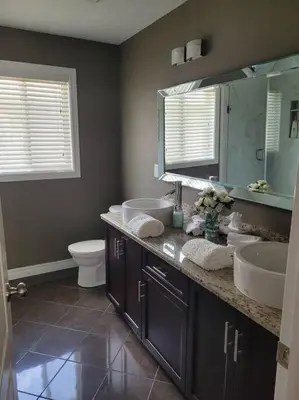 a bathroom with two sinks and a toilet and a mirror at Huge Family home sleeps 10 with 3 parking spots in Kitchener