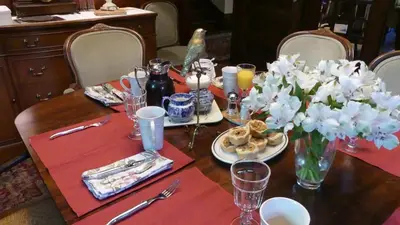 a table with a red table cloth and flowers on it at The Captain's House heritage bed & breakfast in Midland