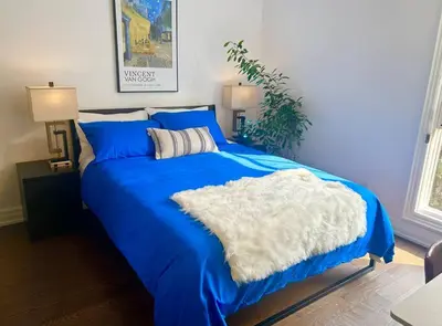 a blue bed with a white blanket on it at Central Toronto in Toronto