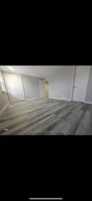 an empty room with a wooden floor and white walls at Affordable Basment Apartment - London in London
