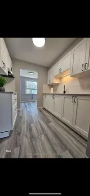 a large kitchen with white cabinets and a wooden floor at Affordable Basment Apartment - London in London