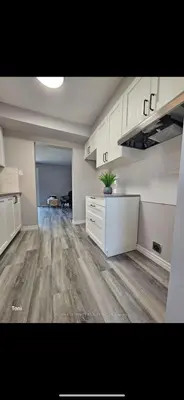 a large kitchen with white cabinets and wood floors at Affordable Basment Apartment - London in London