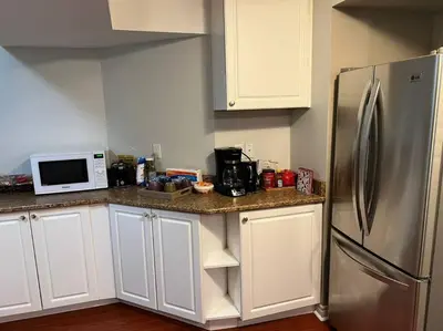 a kitchen with white cabinets and a stainless steel refrigerator at Cozy 2BR Basement Near Two Lakes in Richmond Hill