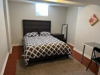 a bedroom with a bed with a black and white comforter at Cozy 2BR Basement Near Two Lakes in Richmond Hill
