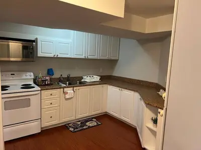 a kitchen with white cabinets and a stove top oven at Cozy 2BR Basement Near Two Lakes in Richmond Hill