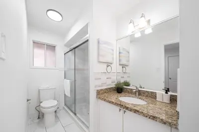a white bathroom with a toilet and a sink at Charming Family Getaway in Richmond Hill in Richmond Hill