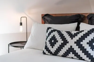 a bed with black and white pillows and a table at Carson's Creek in Hillier