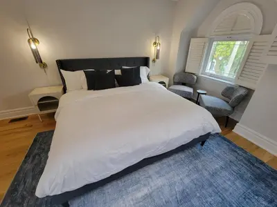 a bedroom with a large white bed and a blue rug at Cozy 3BR Retreat with Dedicated Work table and Parking in Toronto