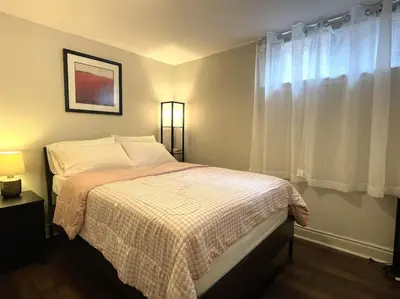 a bedroom with a bed with white sheets and a window at 2 bedroom rental apartment , 1 sofa bed, 2 car parking in Mississauga