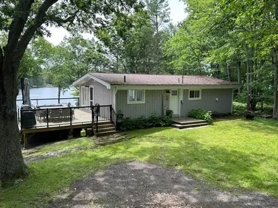 a small house with a dock in the yard at Muskoka Retreat, Fire Pit, Games, Waterfront in Gravenhurst