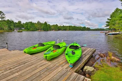 three kayaks sitting on a dock on a lake at Muskoka Retreat, Fire Pit, Games, Waterfront in Gravenhurst