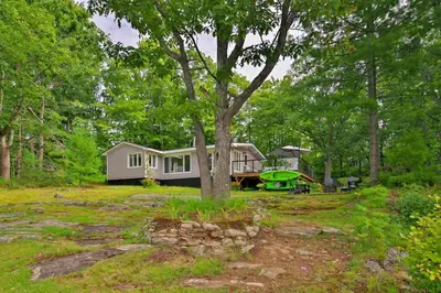 a house in the middle of a yard with a tree at Muskoka Retreat, Fire Pit, Games, Waterfront in Gravenhurst
